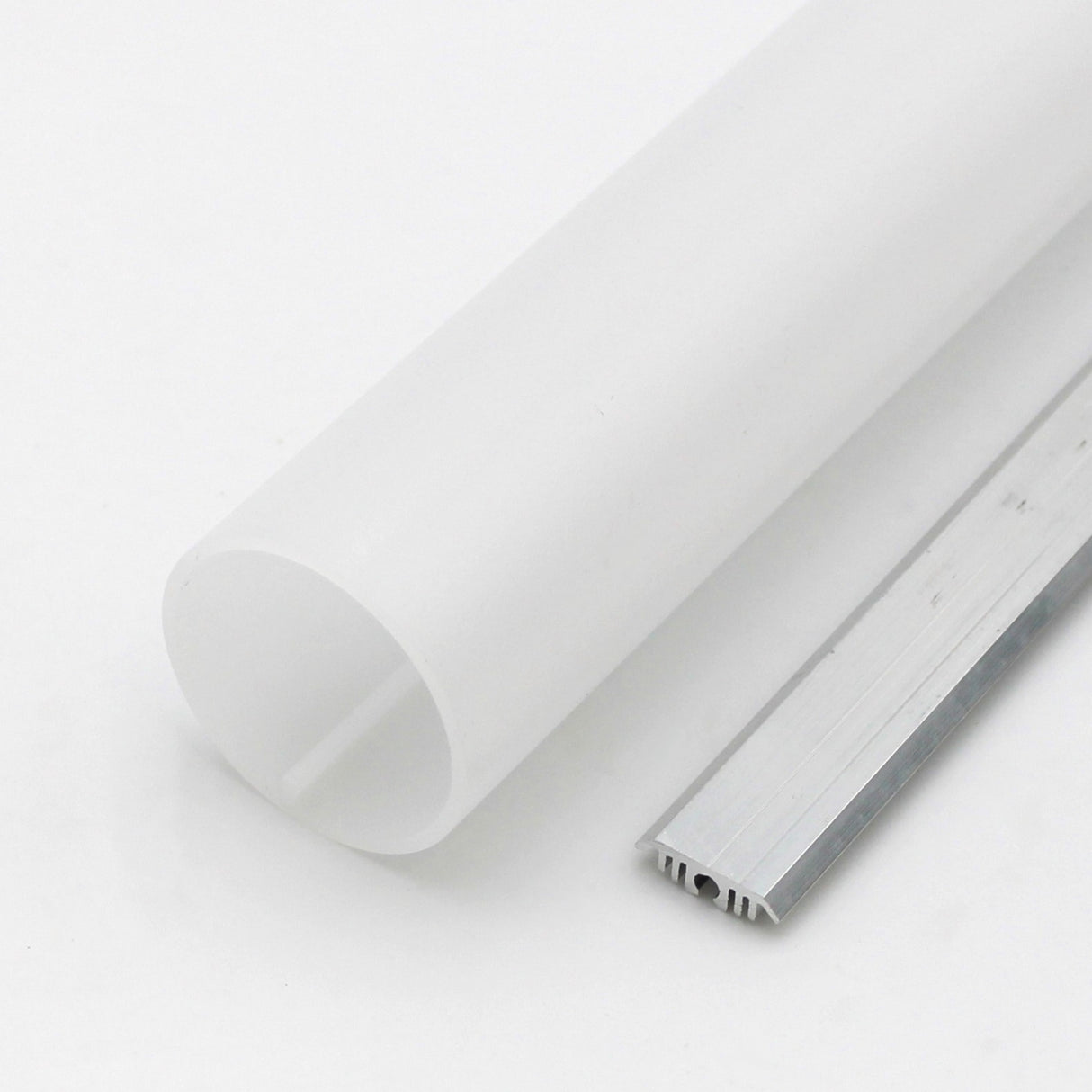 A 1.50" Round Acrylic LED Tube (Model Sierra38) with a frosted finish is seen beside a slim, grooved aluminum channel, both set on a white surface.