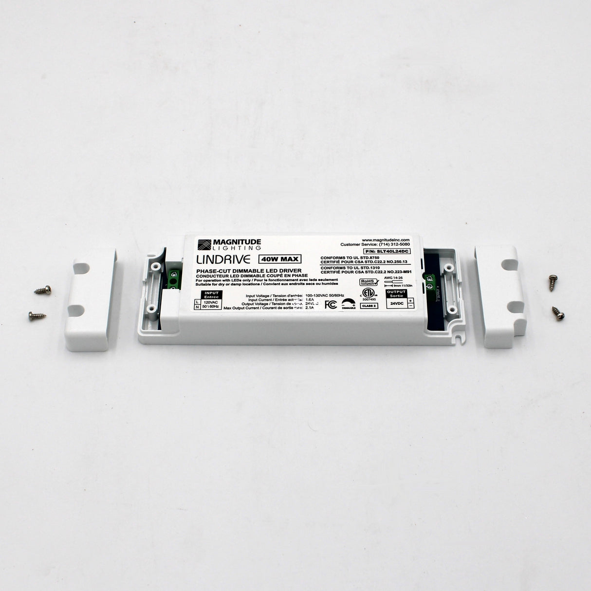 A Compact Electronic Phase Dimmable LED Driver (24V) ~ Magnitude LinDrive, white plastic housing open to show wiring terminals, sits on a white surface with four screws—perfect for under cabinet lighting.