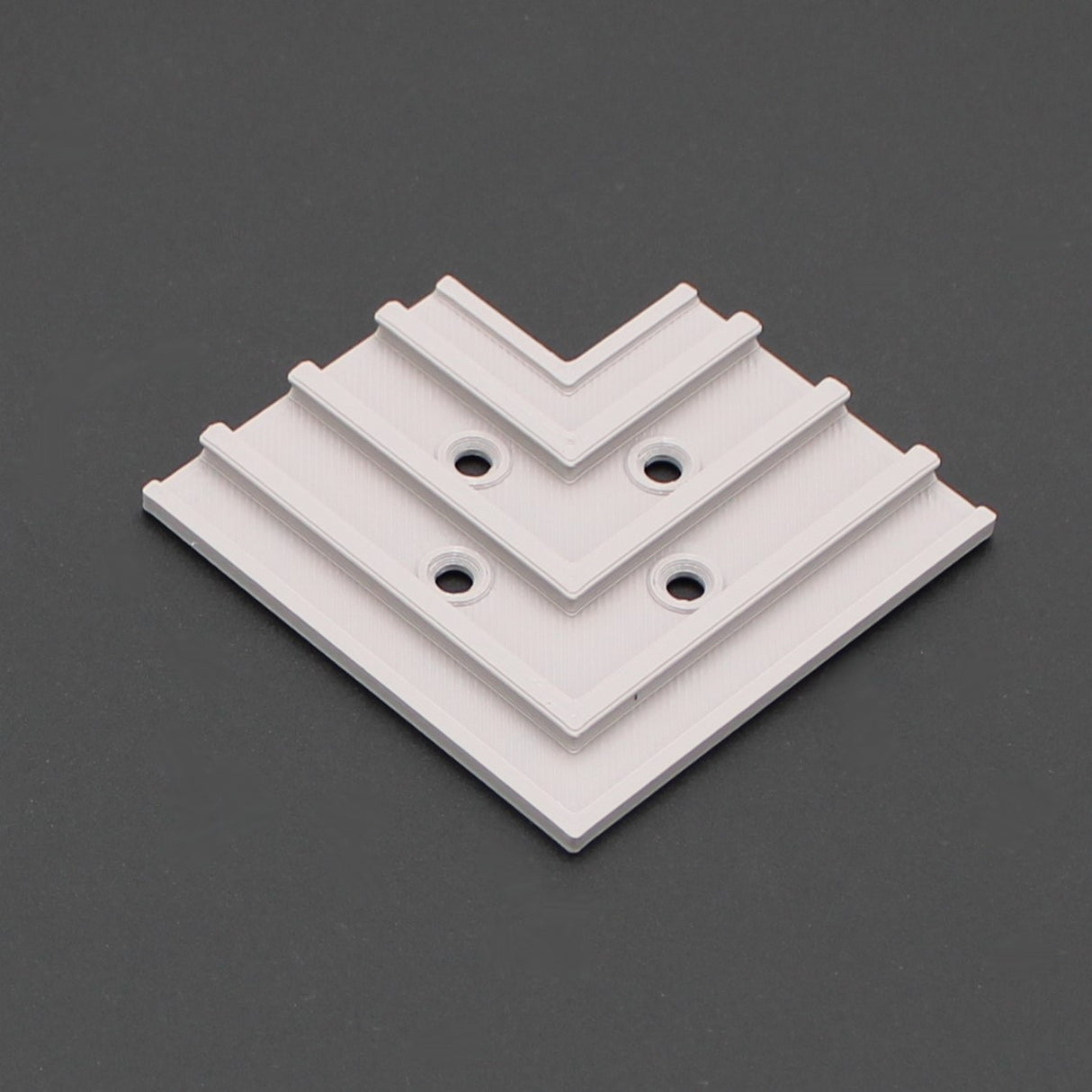 The 3D Printed Hidden Joiner and Bracket for SLW10 Profile is a white, square, ridged bracket with four screw holes in a stepped pattern—ideal as an LED profile extension or joiner. Displayed on dark grey. Available from Wired4signs USA.