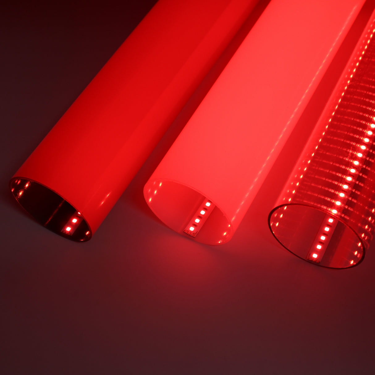 Three cylindrical 2.75 Round Polycarbonate LED Lighting Tubes (Model Smokies70), glowing red with opaque, semi-transparent, and transparent ribbed finishes, create striking diffuser effects against a dark backdrop.