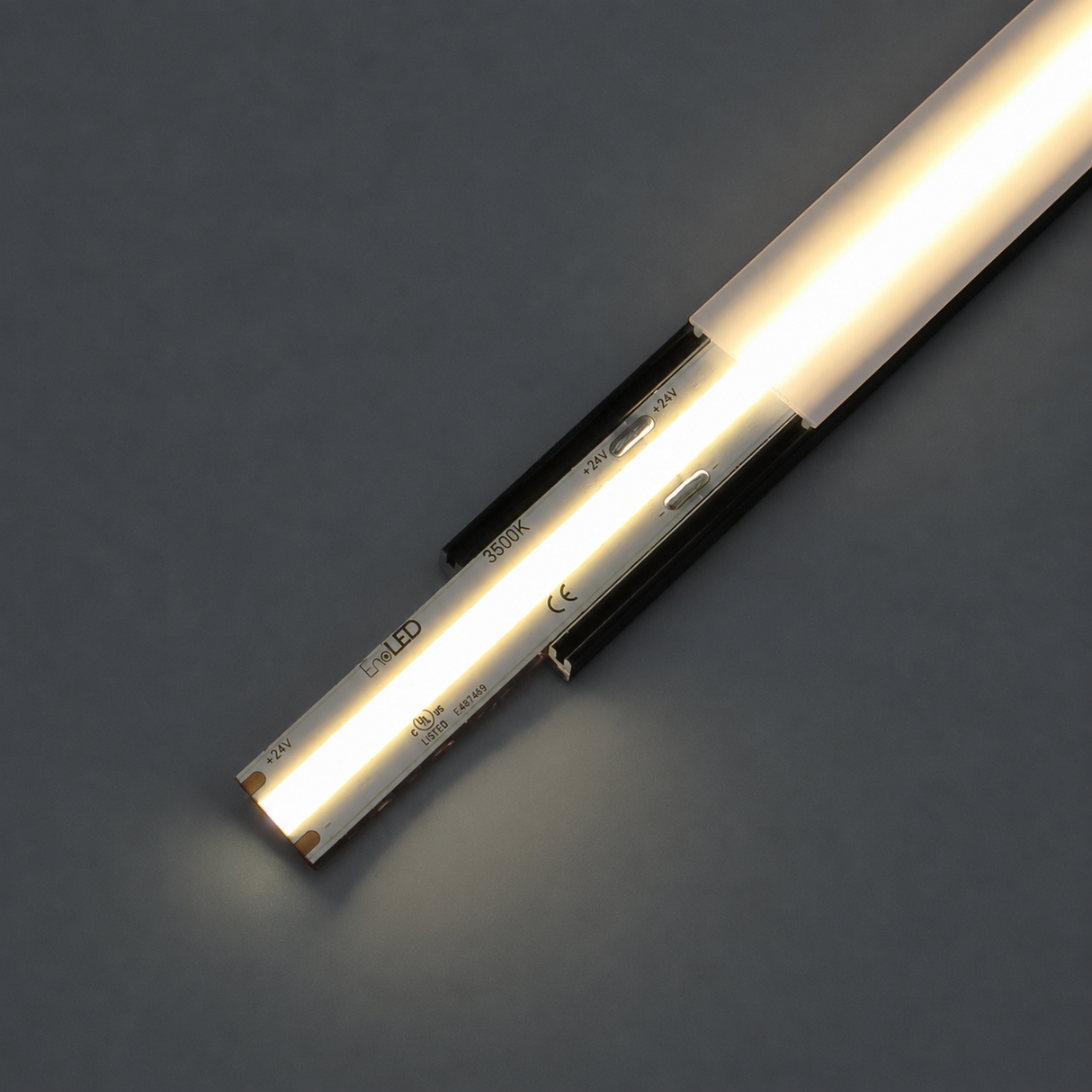 A close-up of the COB IP20 Dotless LED Strip (24V) ~ UniBasic Series on a dark surface, highlighting its bright illumination and the detailed markings along the side of the strip.