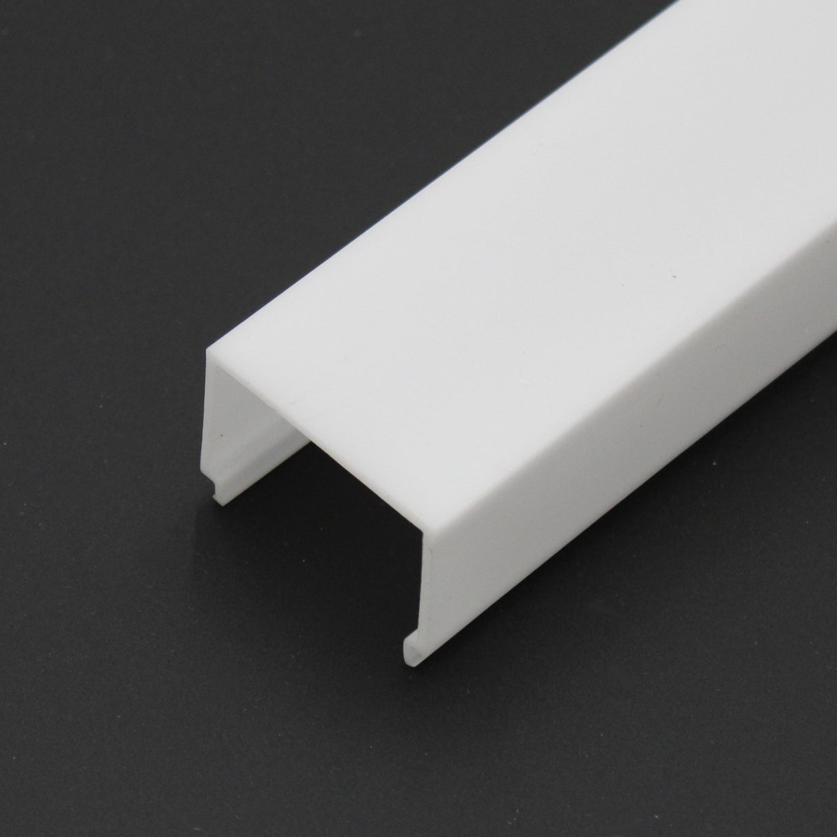 The LED Channel Cover ~ E9 Click is a white, rectangular, U-shaped PMMA channel resting at an angle on a black surface, with open ends visible—perfect as a diffuser or channel for LED lighting projects.