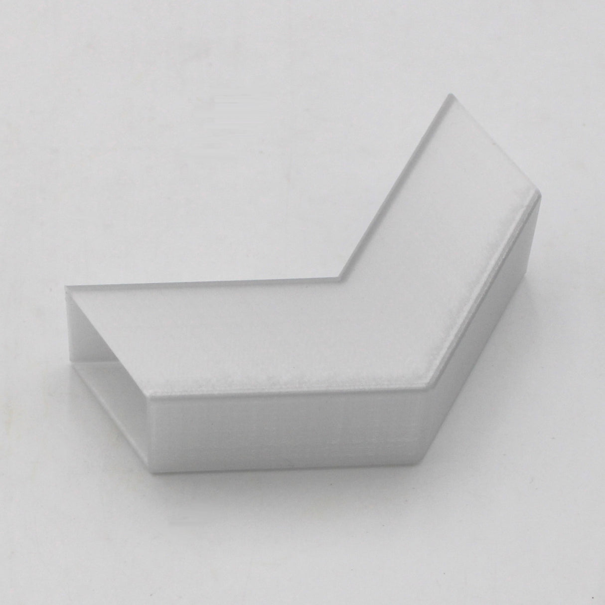 A translucent elbow for the Visby profile, featuring an L-shaped design and a hollow rectangular cross-section, is shown on a plain white background.