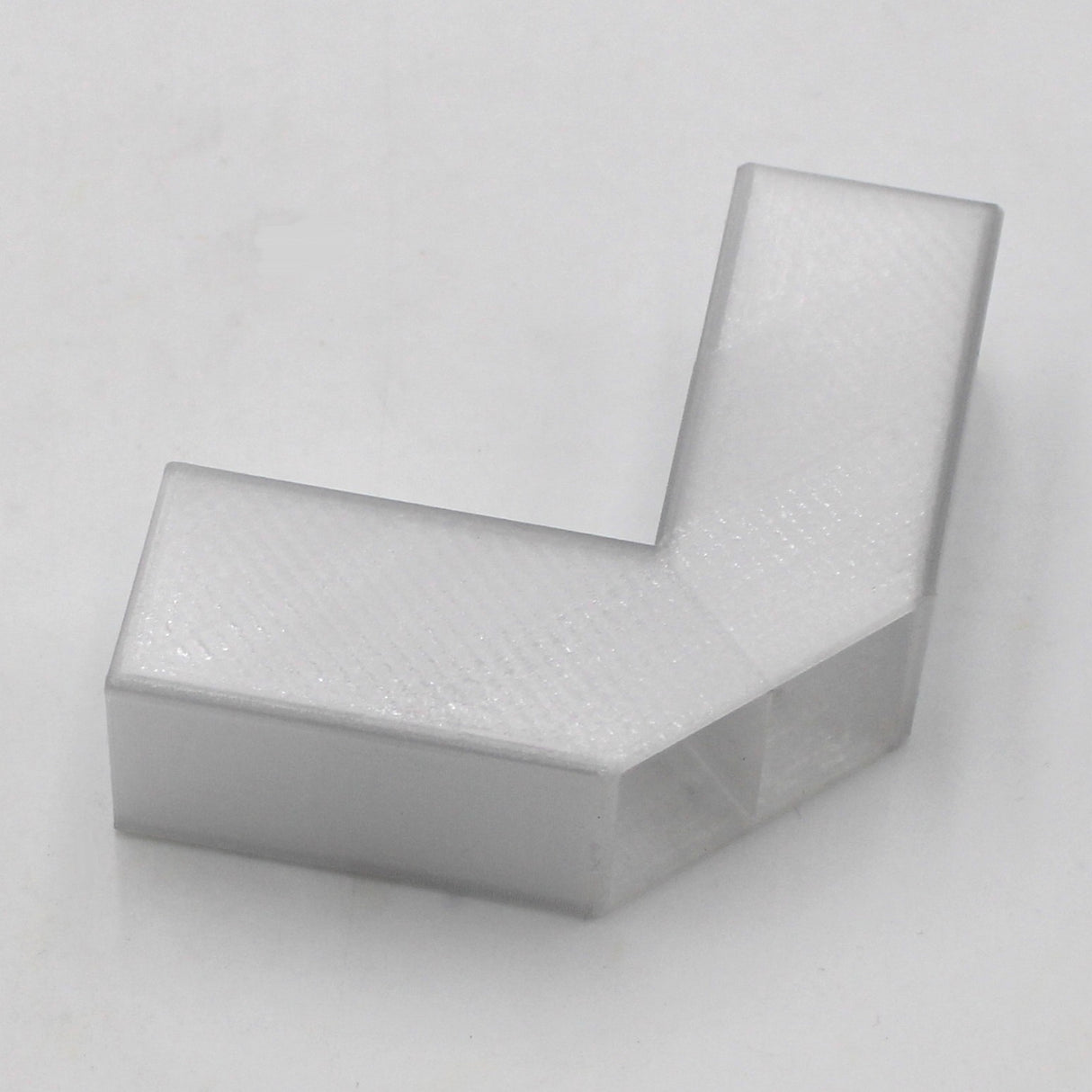 A translucent elbow designed for the Visby profile, made of smooth plastic in an L-shape, is displayed on a plain white background.