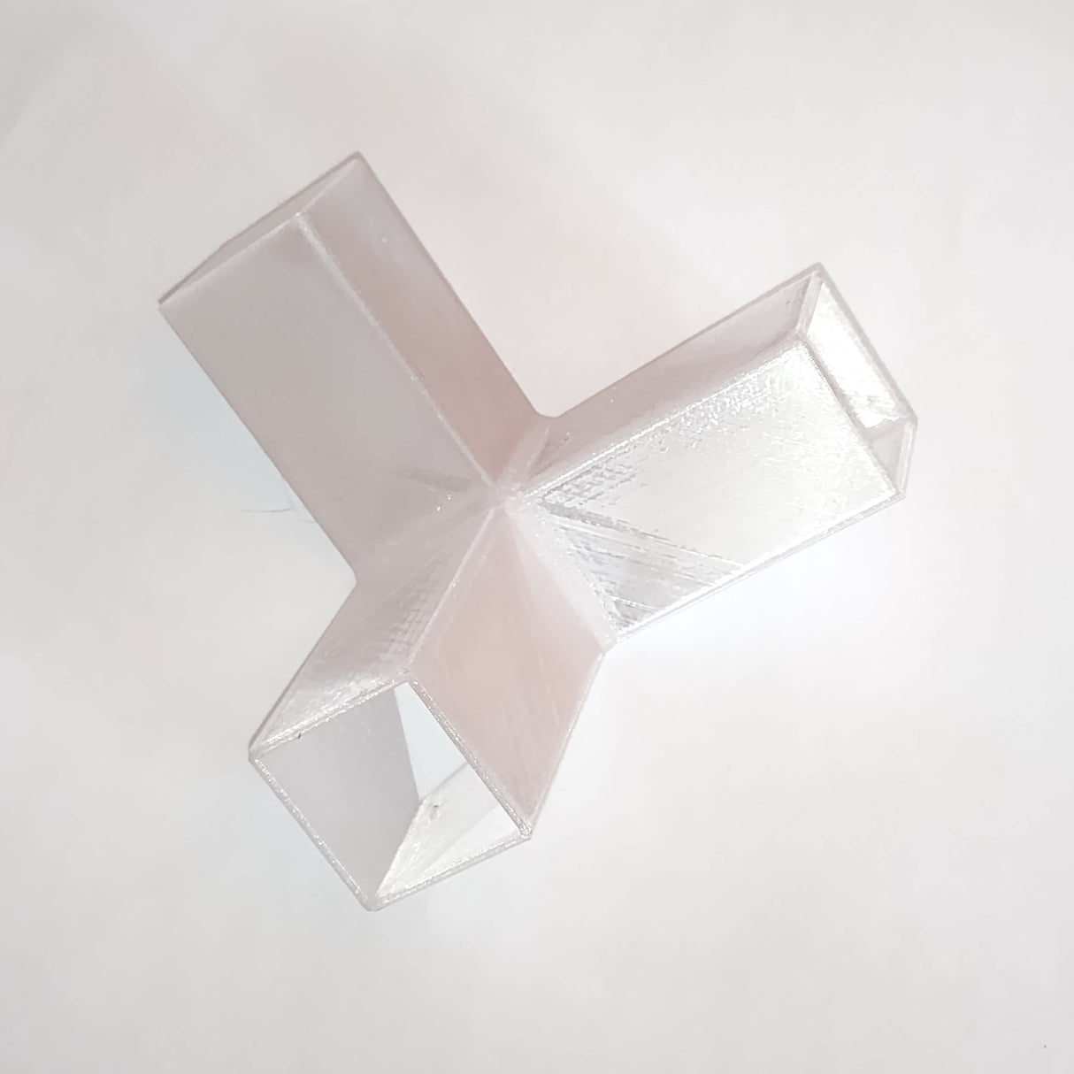 A Translucent Elbow with Crossing for Visby Profile, featuring three rectangular prongs extending from a central junction in a Y or T shape, is placed on a white background.