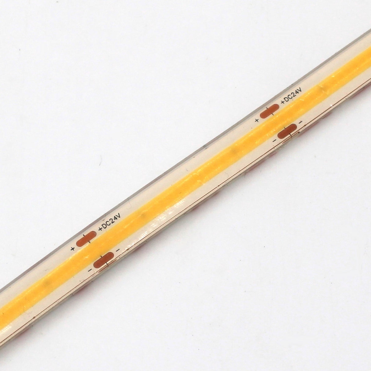 A close-up of the Continuous COB IP67 LED Strip (24V) ~ White Lily Series shows its yellow center strip labeled “+DC24V” and copper contacts, delivering dot-free light on a white background.