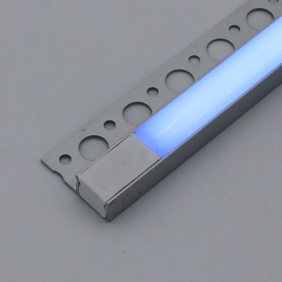 A close-up of the RGB LED Tile Edge Light Strip Kit (24V) ~ Nicho Series, glowing blue and mounted on a perforated metal strip against a plain gray background.
