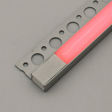 The RGB LED Tile Edge Light Strip Kit (24V) ~ Nicho Series features a metal strip with circular holes and a pink translucent insert, evoking an aluminum LED channel, displayed on a plain light gray background.