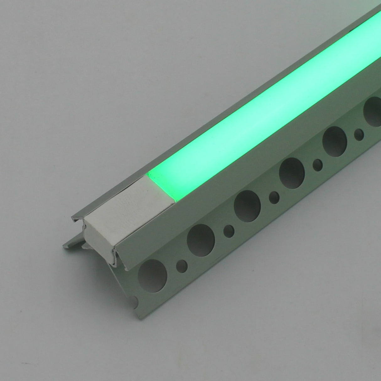 A close-up of the Nicho Series RGB LED Tile Light Strip Kit for Outside Corners (24V) shows its aluminum channel with a glowing green strip, perforated mounting base, and translucent cover.