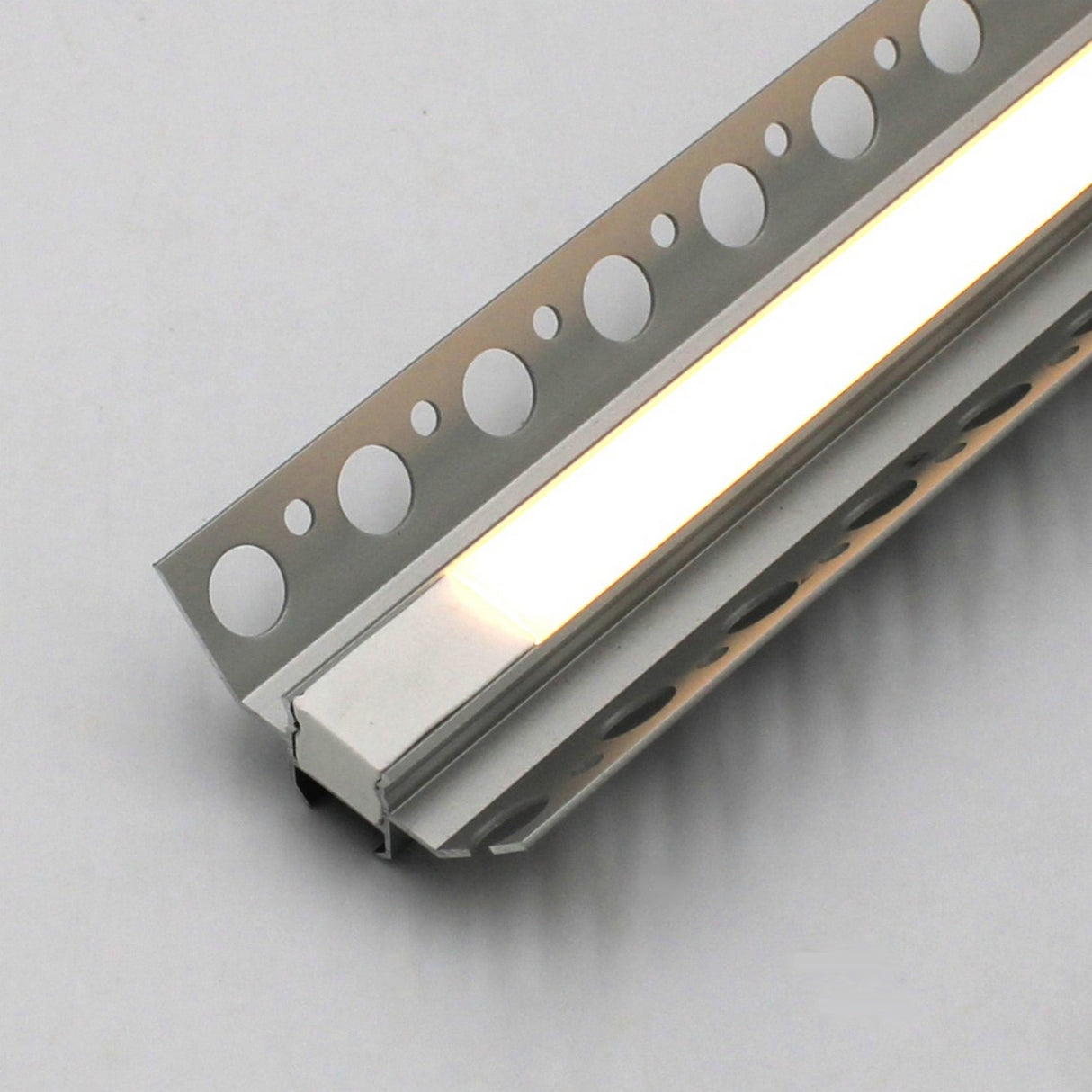 A close-up of the White LED Tile Light Strip Kit for Inside Corners (24V) ~ Nicho Series, encased in a metal housing with circular cutouts, designed for recessed tile installation and emitting soft white light.