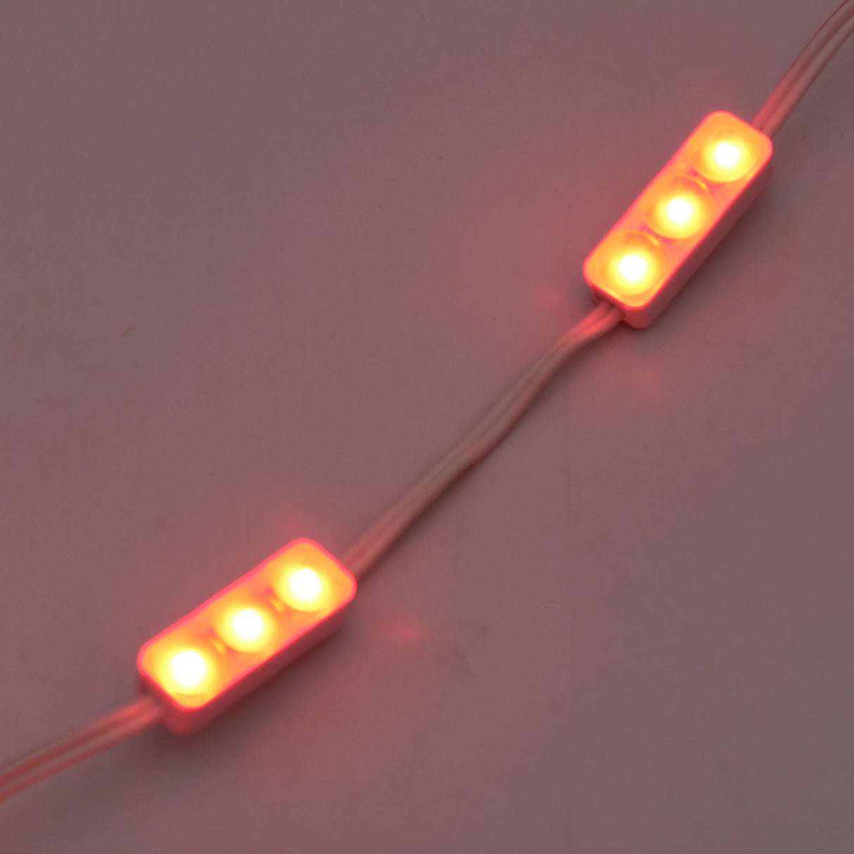 Two white Mini3 Color 160 Mini LED Modules, each with three bright red wide-angle LEDs and white connecting wires, glow against a plain background. IP68 waterproof, they offer reliable lighting for diverse environments.