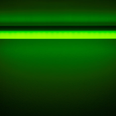 The Colored Border Contour Tube Light ~ Hi-Lite 30 Straight Section casts green light onto a dark wall from above, creating a vivid glowing gradient of green across the surface.