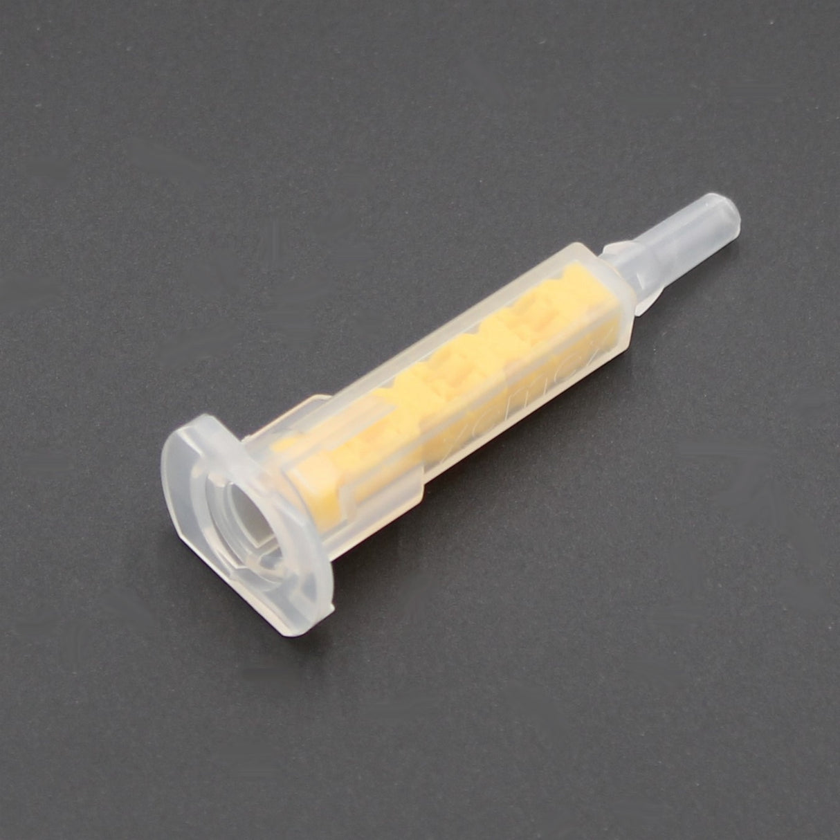 A close-up of the Xemex A-System Bayonet High-Performance All-Ratio Mixer for 2-Part Methacrylate, featuring a yellow interior and clear plastic body, shown on a dark gray surface.