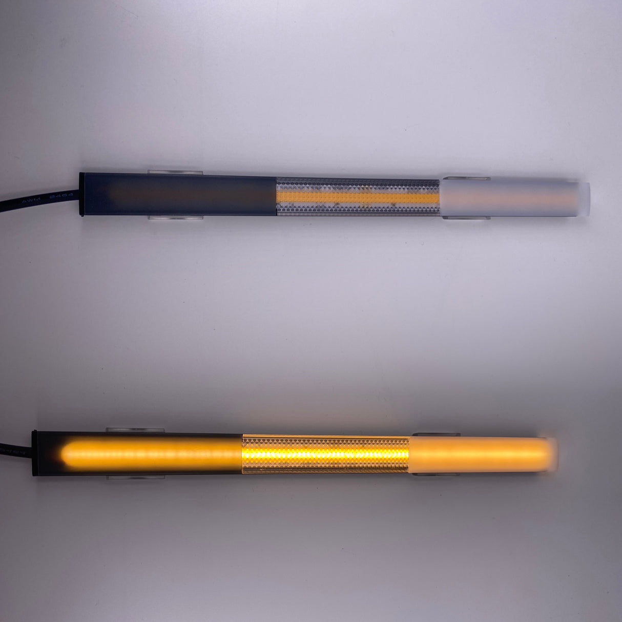 Two horizontal Ultra Thin Bendable LED Strip Channels (Model Milano Slim) are mounted on a white wall. The lower channel emits a warm yellow glow, accentuating the sleek, metallic and translucent ultra-thin profile; the upper channel is off.