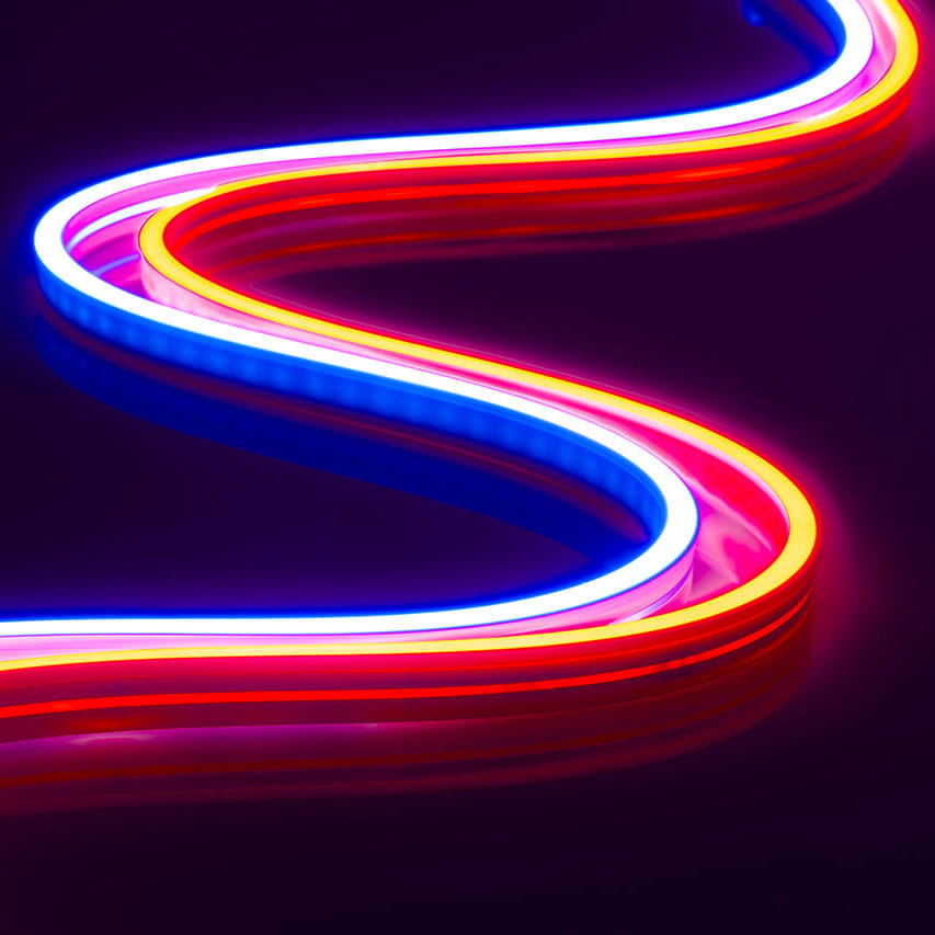 A wavy Pixel IP44/IP66 Neon Flexible LED Light Line (24V) ~ Flex Super Slim Series in red, blue, and pink glows across a dark purple background.