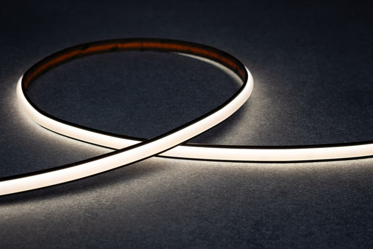 The Optimum Black Neon Max Series Black IP65 Neon LED Light Line (24V) forms a loose loop on a dark, textured surface, emitting a bright, even glow.