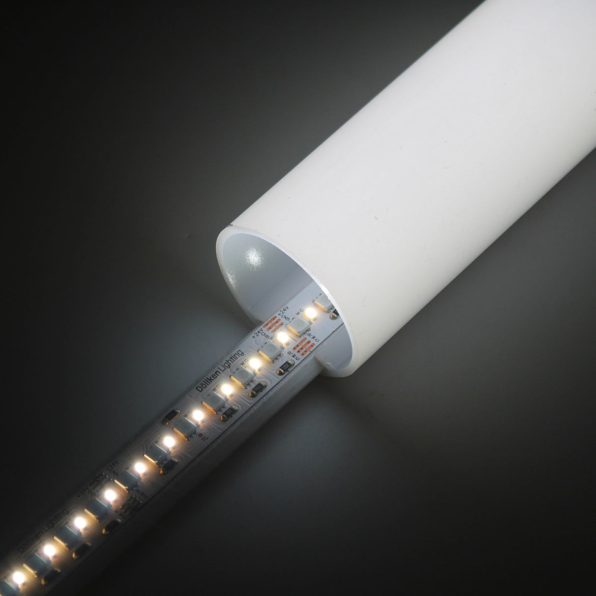 A close-up of the RGB+CCT IP20 LED Strip (24V) ~ Optimum Cromatic Series glowing inside a white cylindrical tube against a dark background, highlighting its tunable white lighting.