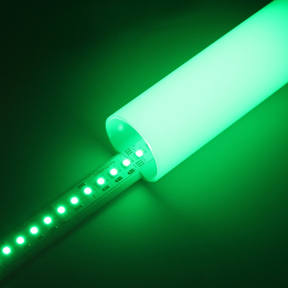 A partially inserted RGB+CCT IP20 LED Strip (24V) ~ Optimum Cromatic Series glows green inside a translucent cylinder, casting vibrant green light into the surrounding area.