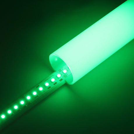A partially inserted RGB+CCT IP20 LED Strip (24V) ~ Optimum Cromatic Series glows green inside a translucent cylinder, casting vibrant green light into the surrounding area.