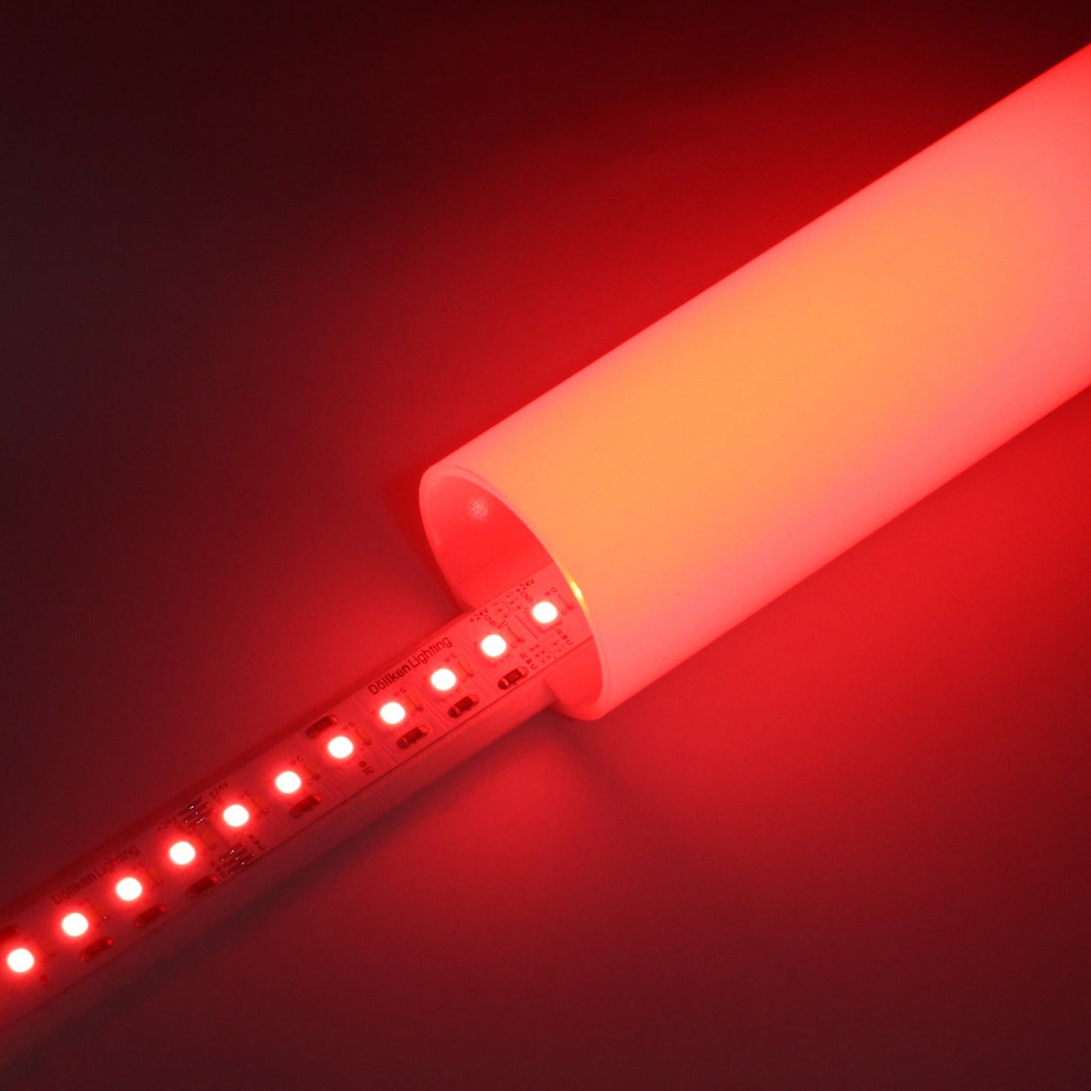 A close-up of the RGB+CCT IP20 LED Strip (24V) ~ Optimum Cromatic Series glowing red inside a translucent white tube, brightly illuminating the area and highlighting its energy efficiency.
