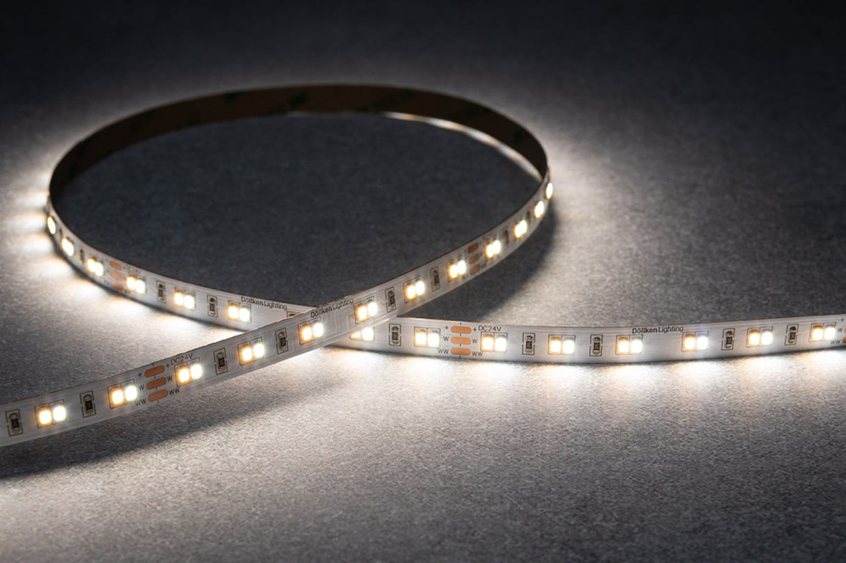 The High-CRI Tunable White IP20 LED Strip (24V) ~ Optimum Harmony Series emits a bright white glow while arranged in a curved pattern on a gray textured surface.
