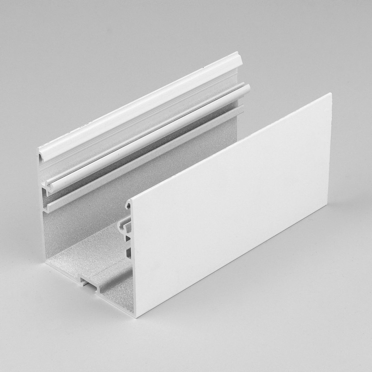 The 2 Suspended/Surface Mount Ceiling LED Strip Channel ~ Model Phil.v2 is a white, rectangular LED profile with grooves and a flat panel, designed for construction or commercial lighting assemblies. Shown on a plain light gray background.
