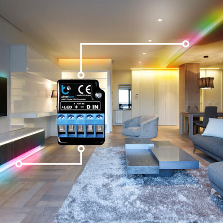 A modern living room features colored LED strip lighting along the ceiling, controlled by the Wi-Fi RGB Pixel LED Controller ~ pixelBox by BleBox, showcasing smart home lighting automation.