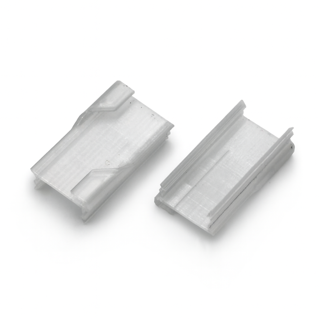 Two small, clear Roma XL Drop Ceiling Clips with angled edges and grooves sit side by side on a white background—perfect 3D printed push-fit clips for mounting the Roma XL profile to a drop ceiling.