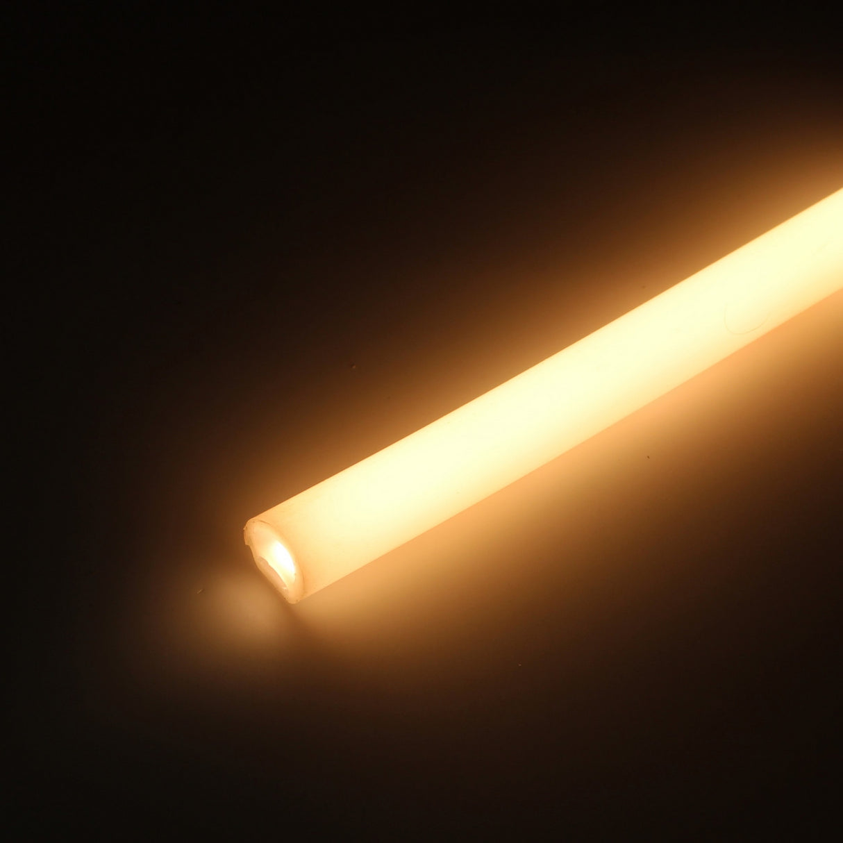 The Flexible Diffuser for LED Strip ~ Model Neon Redondo XL emits a warm yellowish-white glow from its cylindrical shape, standing out beautifully against a dark background.