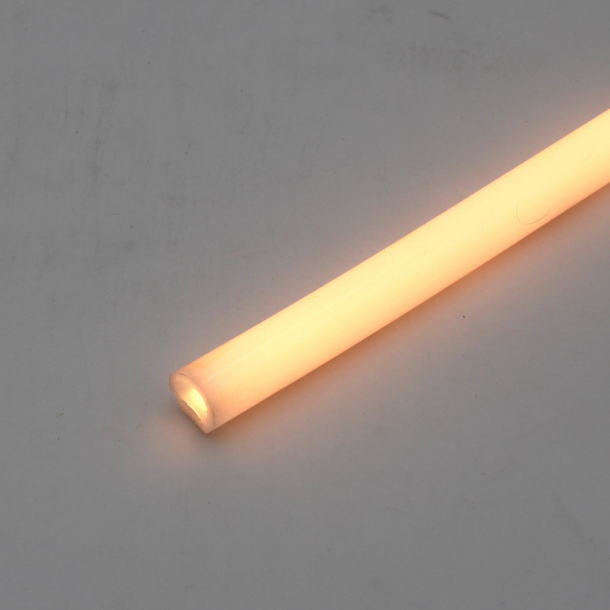 The Flexible Diffuser for LED Strip ~ Model Neon Redondo XL with a silicone cover is displayed glowing orange against a plain light gray background.