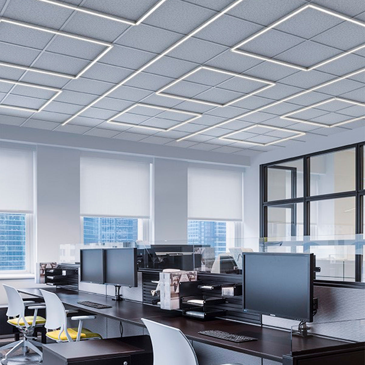 A modern office with several desks, computers, white chairs, and large windows. The ceiling features geometric Waterproof LED Channel ~ Model Roma Easy On IP65 lighting, and natural light fills the space.