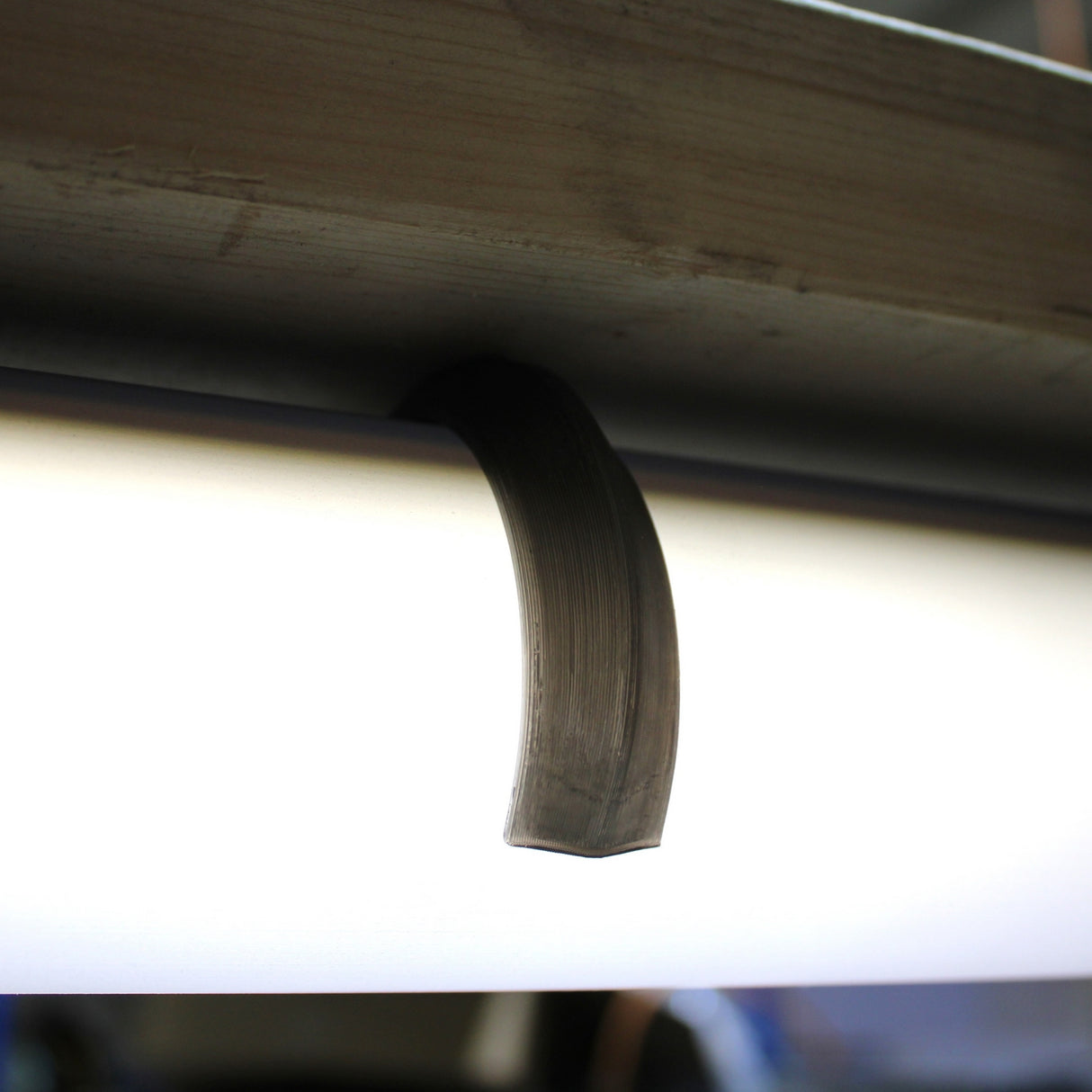 A Mounting Clip for 2.56" Round Profiles secures a fluorescent tube, shown with a crescent-shaped smudge on its surface, beneath a metal fixture.