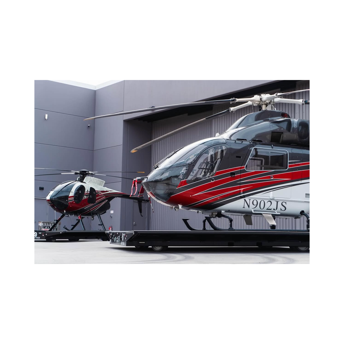 Two helicopters parked on transport dollies in front of a gray hangar illuminated by an Up-and-Down Stair Lighting LED Channel ~ Model Niza Duo.