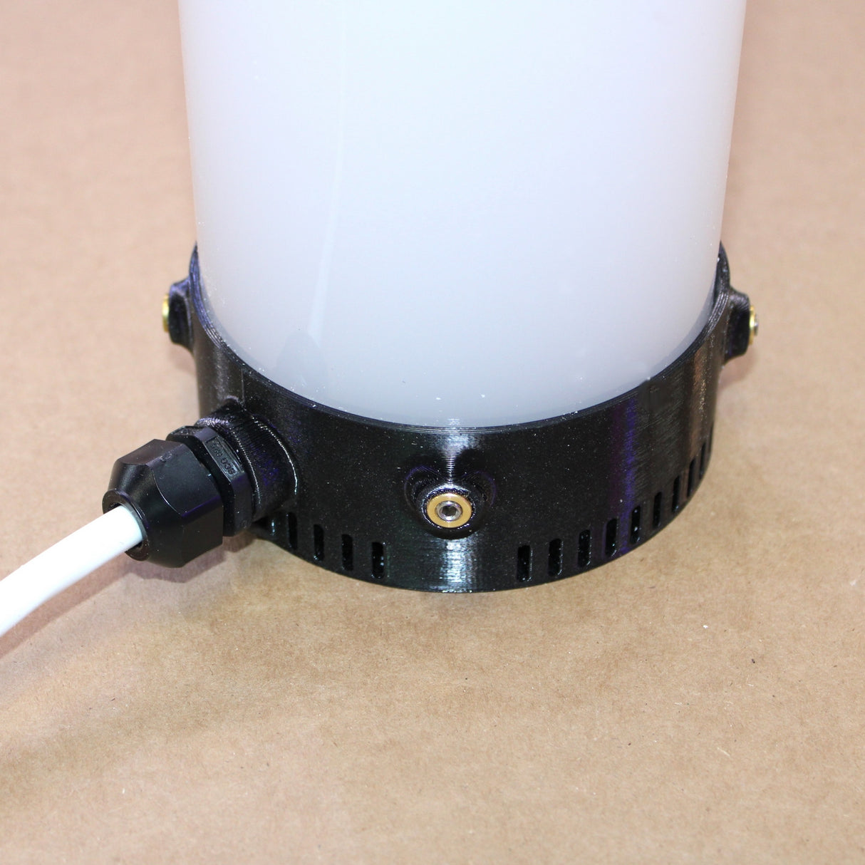 Close-up of the Plastic Base for Smokies100 Profile diffuser: a cylindrical white base with a black plastic bottom, surface-mount vents, and a white power cable connected at the side, positioned on a light brown surface.