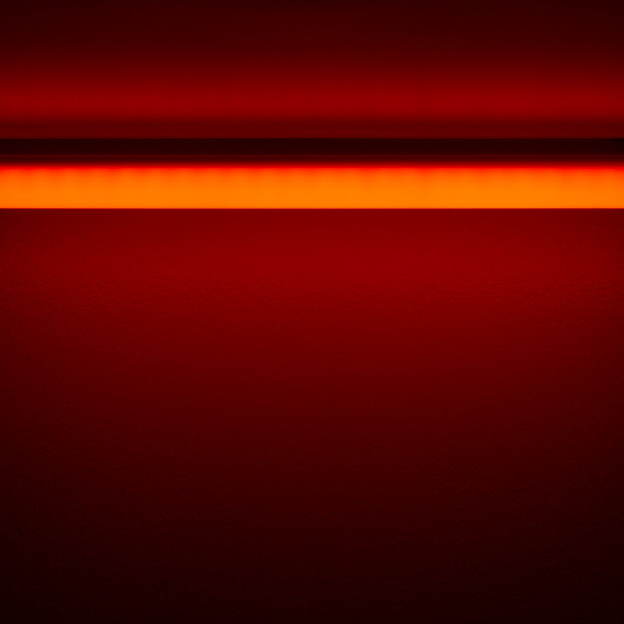 The Colored Border Contour Tube Light ~ Hi-Lite 30 Straight Section casts a horizontal orange-red glow on a dark red wall, forming a vivid bright band at the top that gradually fades into deeper red shades below.