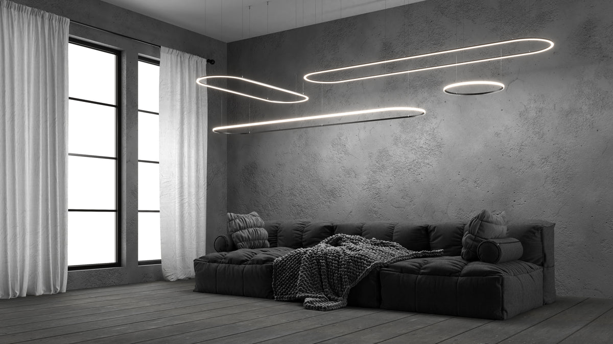 Three elongated, curved installations of 0.51″ Suspended/Surface Mount Bendable LED Channel ~ Model Bend8 suspended from the ceiling above a low-profile sofa in a modern room.