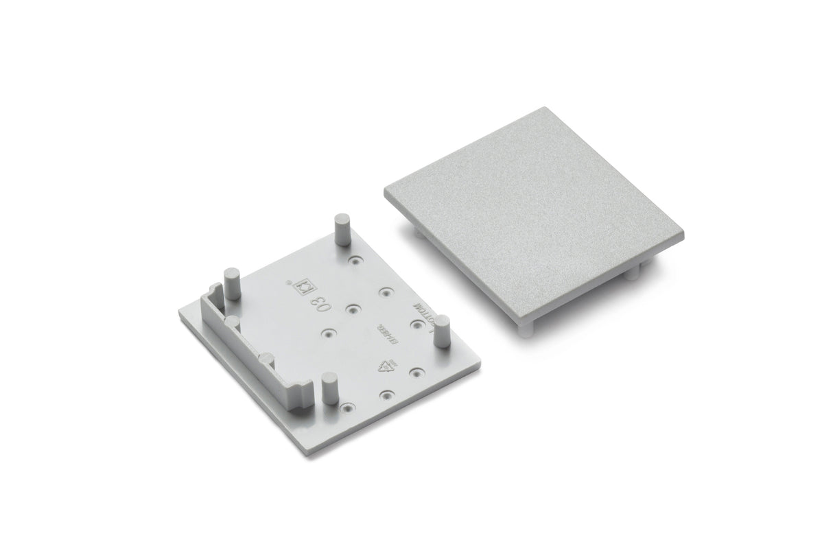 Two gray plastic End Caps for Vario30-03 Profile are shown side by side on a plain white background—one with pegs and markings facing up, the other as a flat cover. Perfect for lighting fixture installations.