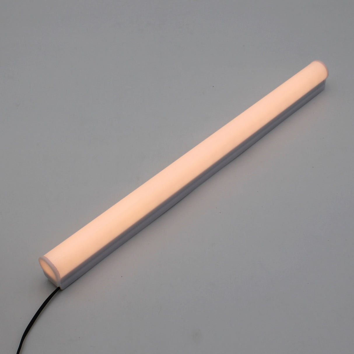 The White Border Contour Tube Light ~ Hi-Lite 30 Straight Section features a glowing LED in a white casing with a black power cord, ideal for building illumination and easy mounting using included polycarbonate clips.