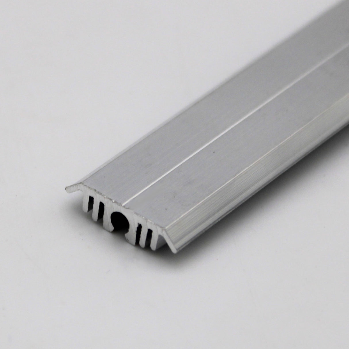 A close-up of the Flat Bar Aluminum Heatsink LED Profile ~ Model Yukon shows its grooved, ribbed silver strip on a white background, featuring a flat top and toothed underside for sealing or edging uses.