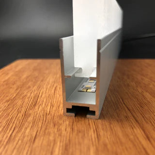 Close-up of the Edge-lit Acrylic Sign Base Channel ~ Model Hannover with a white diffuser, shown on wood. This channel is designed to house LED light strips, making it perfect for illuminating LED edge-lit acrylic signs.