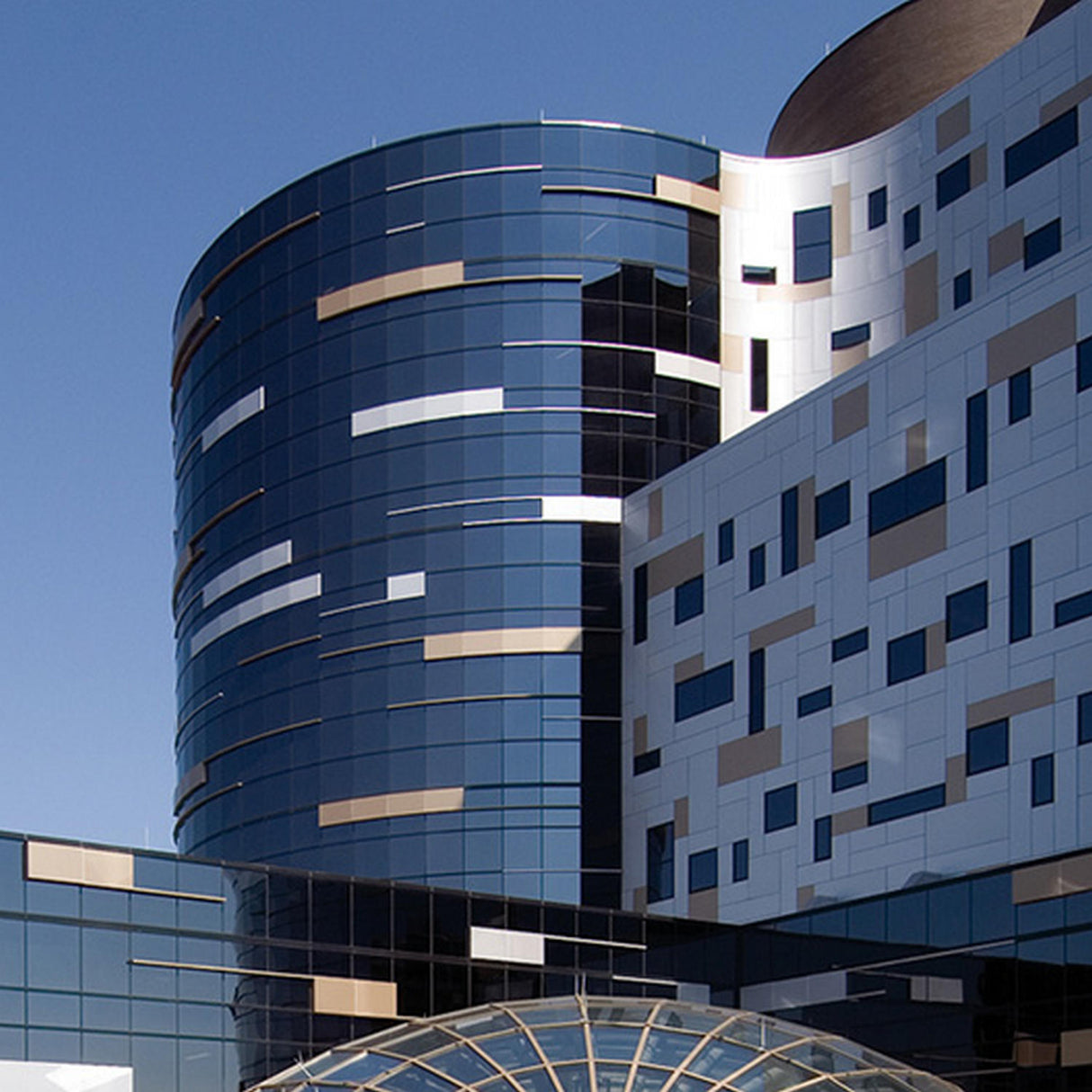 A modern building with curved glass windows and a white facade featuring irregularly placed beige and black ALPOLIC/fr Series fire-resistant aluminum composite material panels, set against a clear blue sky.