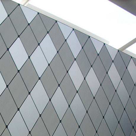 A wall of diamond-shaped ALPOLIC/PE Series lightweight aluminum composite panels in gray tones, featuring a skylight and beams above that let in natural light—perfect for innovative building applications.