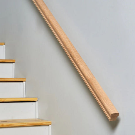 A Solid Wood LED Handrail Profile ~ Model Appalachians Wood is mounted diagonally on a white wall beside a staircase with white steps and light wooden treads.