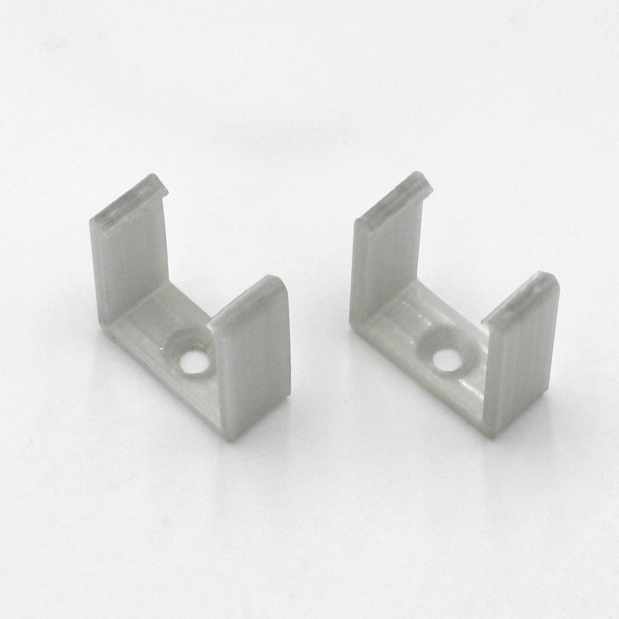 Two small, white plastic U-shaped Mounting Clips for Visby Profile, each with a central hole in the base, are displayed on a plain white surface.