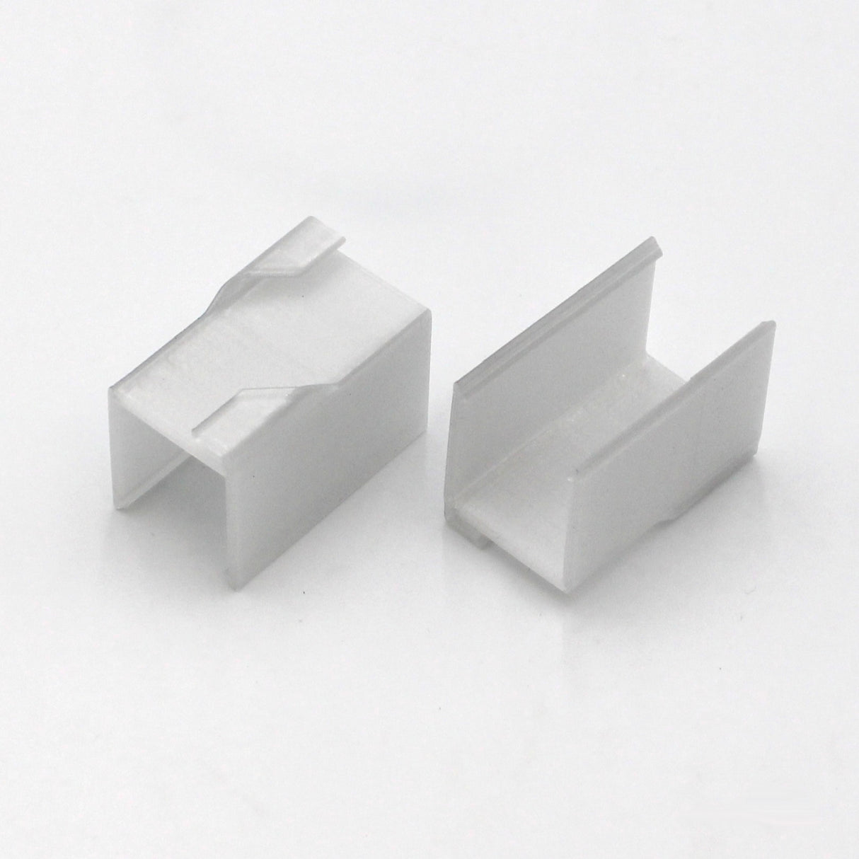 Two small, white, rectangular Visby Drop Ceiling T-Bar Clips with open U-shaped channels are shown on a white background at different angles to display their shape and structure—ideal for mounting to Visby profiles.