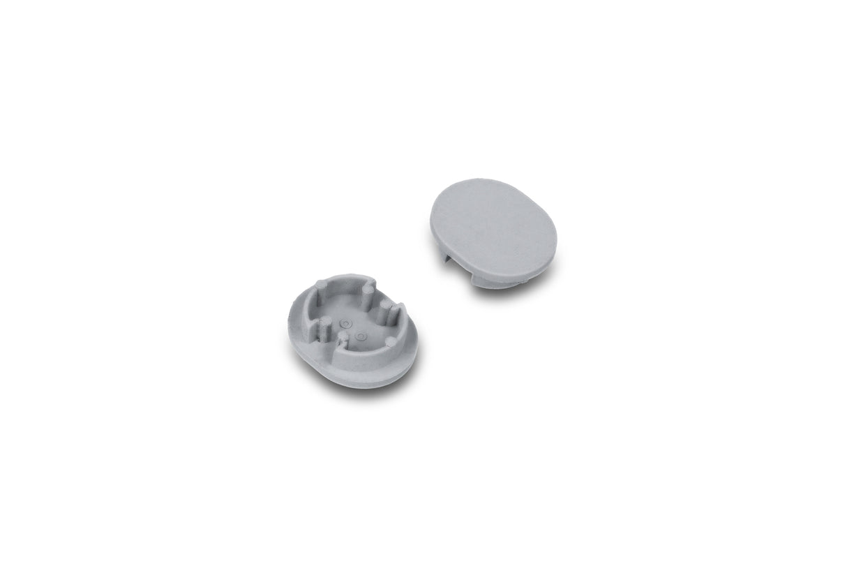Two small, gray, oval plastic D End Caps for the Arc12 Duo Profile lighting fixture are shown; one end cap is positioned with the interior side facing up to reveal small ridges, while the other displays its smooth exterior surface. The items are set against a white background.
