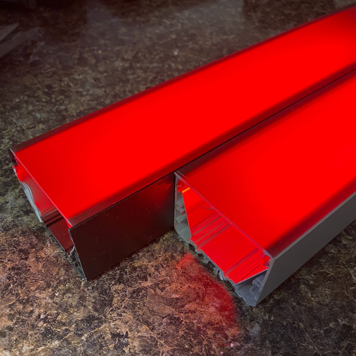 Two Black Diffusers for PL55-FL Profile emit a vivid red glow and feature a sleek, rectangular LED design with frosted covers, displayed side by side on a dark textured surface.