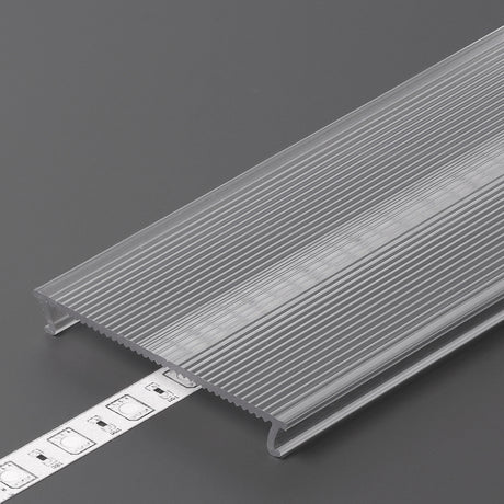 The LED Channel Cover ~ C10 Click, a translucent ribbed opal PMMA profile, partly conceals a white LED strip light on a gray surface as a tape measure displays the width.