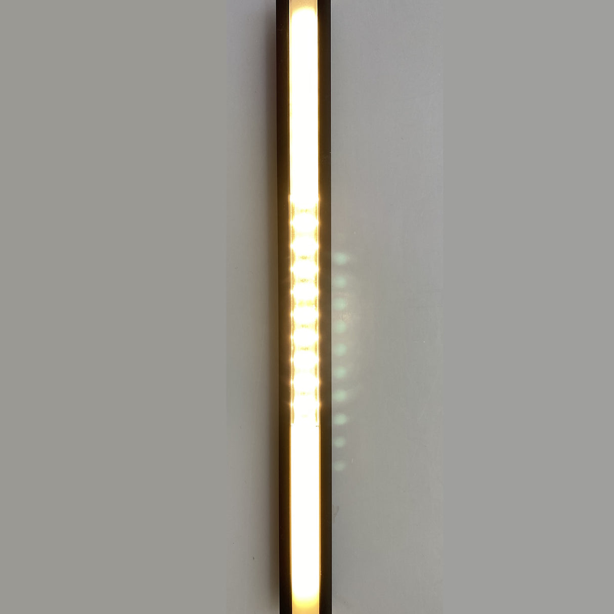 The 0.39 Recessed LED Channel ~ Model Smart-In10 emits a sleek, dot-free line of bright white light vertically, creating a subtle reflection on a plain, light gray wall.