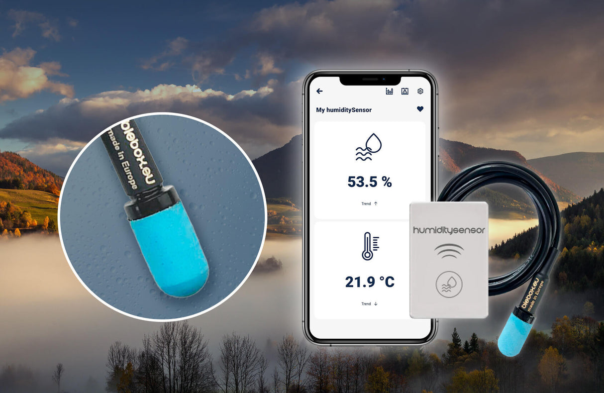 The Smart Wi-Fi Air Temperature and Humidity Sensor ~ humiditySensor by Blebox, featuring a blue tip, is placed beside a smartphone showing temperature data, with misty hills visible in the background.